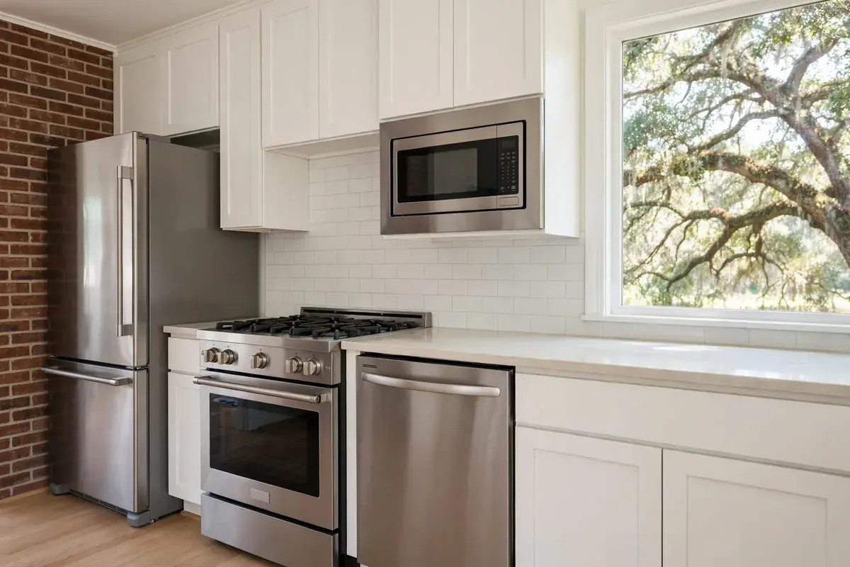 Home kitchen showing a refrigerator, range, dishwasher and microwave in one row beneath a window